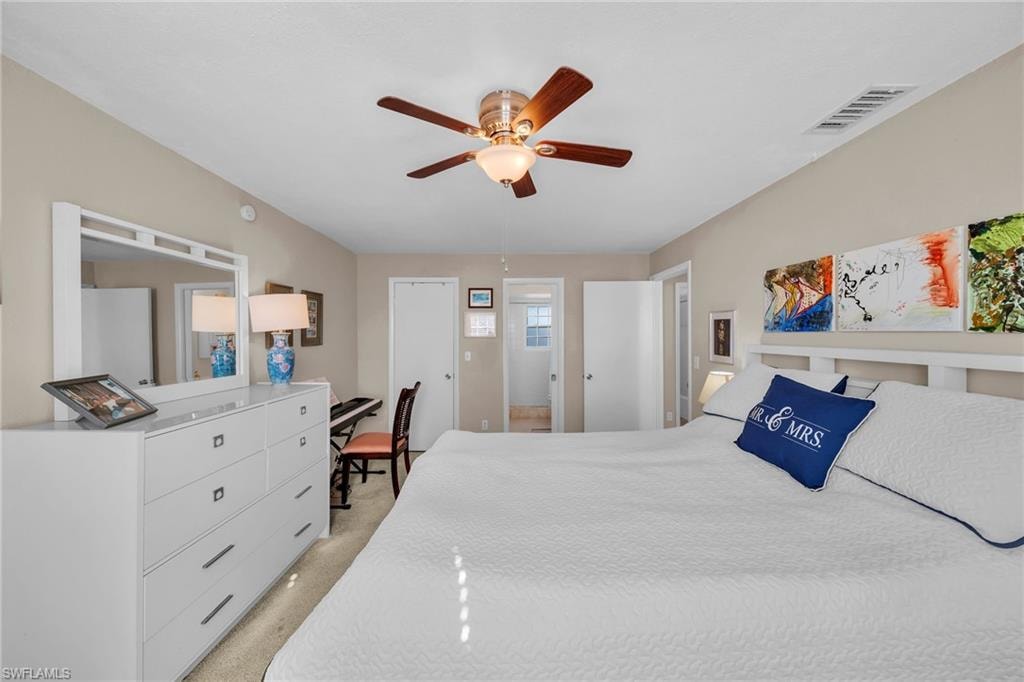 Carpeted bedroom with a vaulted ceiling, wood-finish ceiling fan, and light neutral wall paint