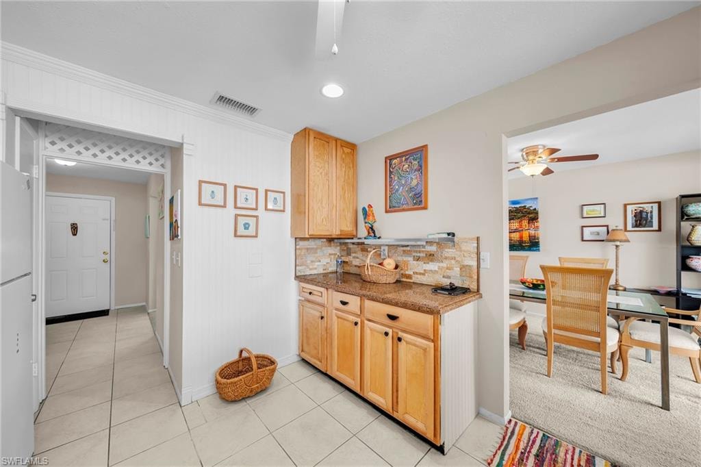 Kitchenette area featuring wood cabinetry, stone-look countertops, and a stacked stone backsplash
