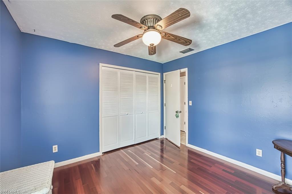 Unfurnished bedroom featuring wood finished floors, a textured ceiling, a closet, and ceiling fan