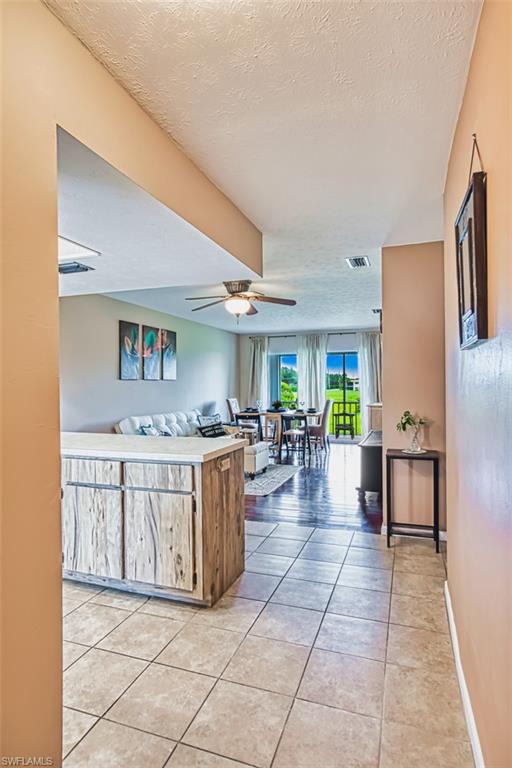 Kitchen with light tile patterned flooring, a textured ceiling, ceiling fan, open floor plan, and light countertops