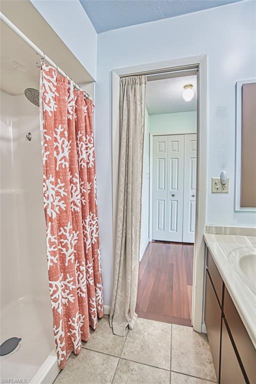Bathroom with a shower with curtain, tile patterned floors, and vanity