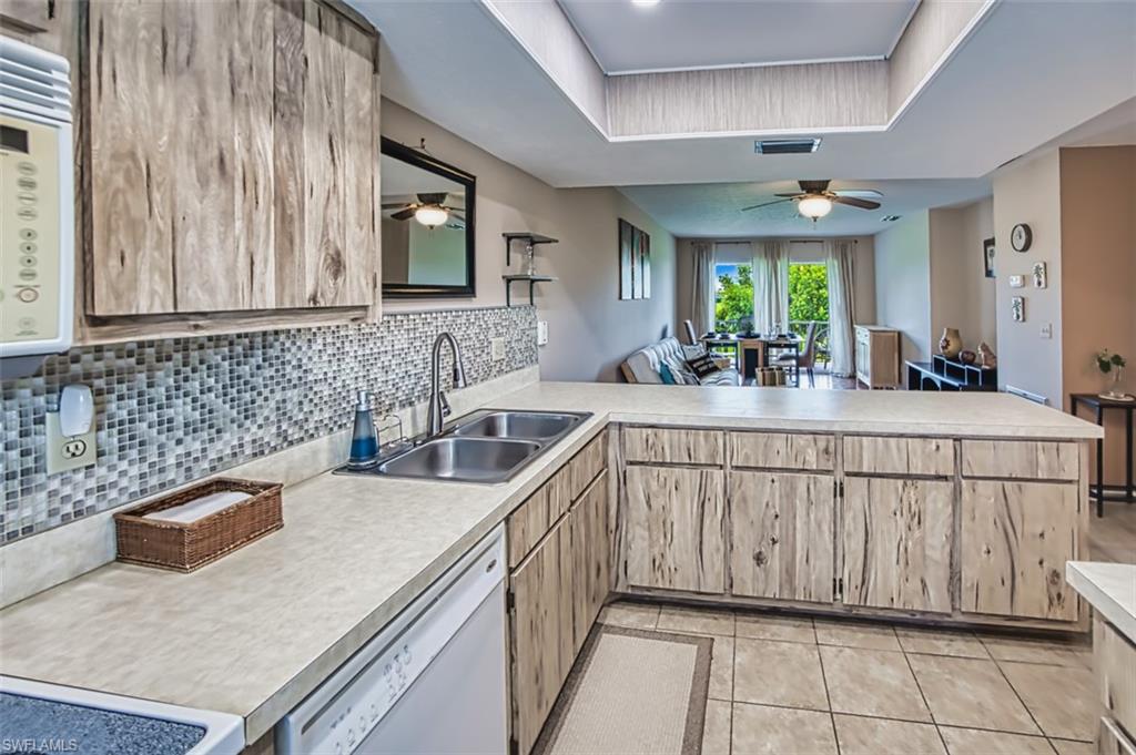 Kitchen featuring a ceiling fan, light countertops, a peninsula, white appliances, and light tile patterned floors