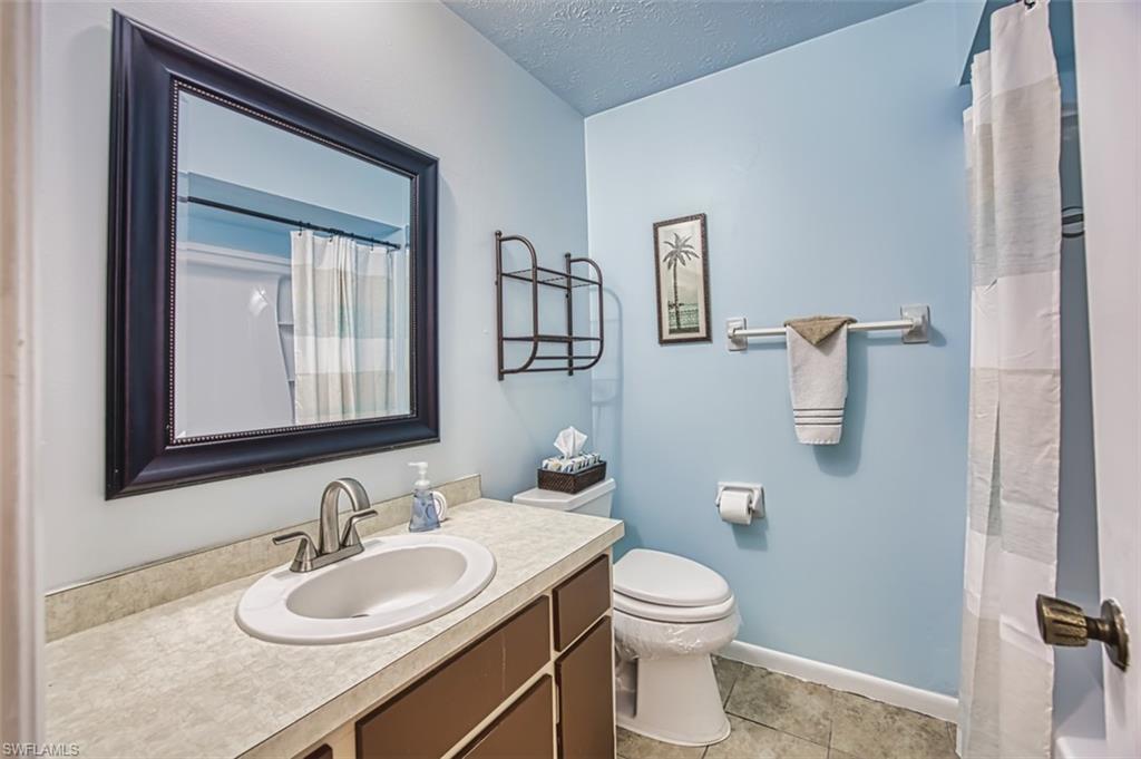 Full bath featuring vanity, a textured ceiling, tile patterned flooring, and curtained shower