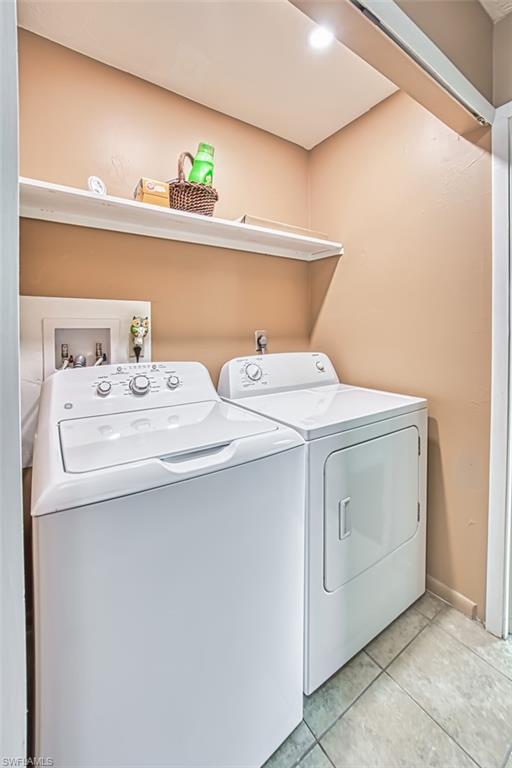 Washroom featuring washing machine and clothes dryer and light tile patterned flooring