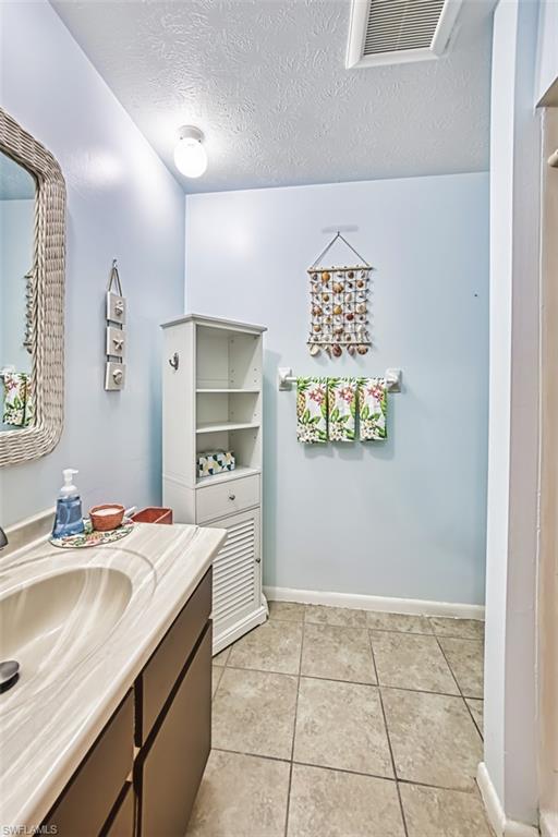 Bathroom featuring vanity, a textured ceiling, and tile patterned flooring