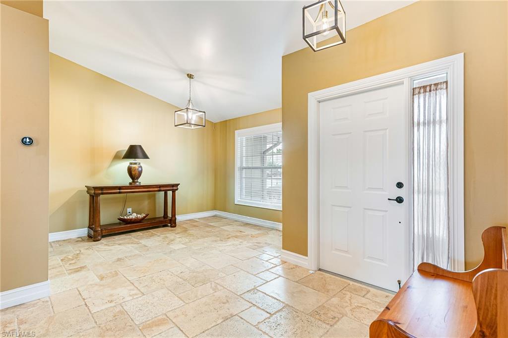Foyer featuring large format tile flooring, a white paneled entry door with sidelight, and two contemporary geometric pendant lights - Virtually Edited Image