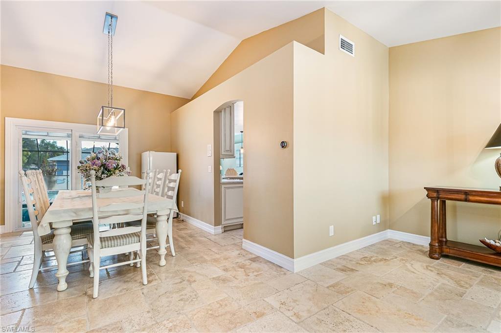 Vaulted ceiling dining area featuring neutral-toned floor tile and sliding glass doors - Virtually Edited Image