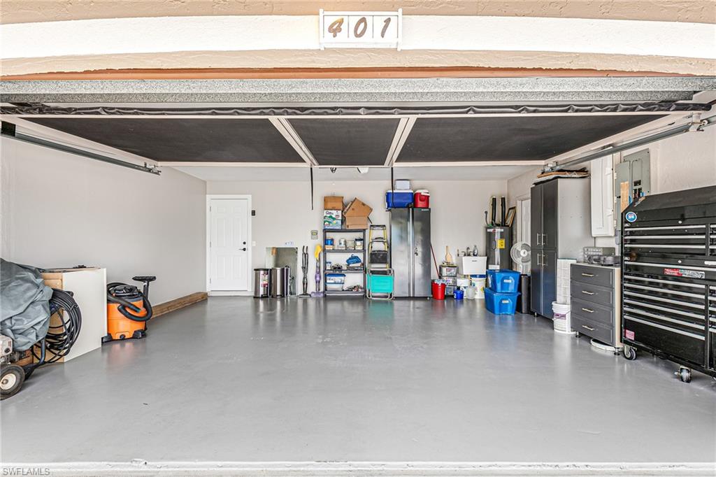 Spacious garage featuring a durable concrete floor, an interior access door, and overhead lighting - Virtually Edited Image