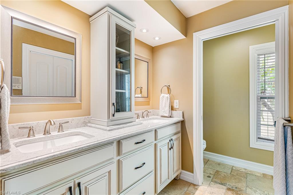 Dual vanity featuring white cabinetry, undermount sinks, and light-toned countertops - Virtually Edited Image