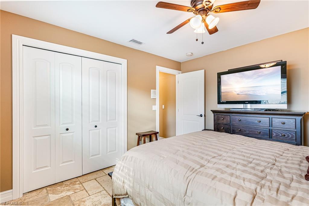 Bedroom featuring bi-fold closet doors, a ceiling fan with light fixture, and tile flooring - Virtually Edited Image