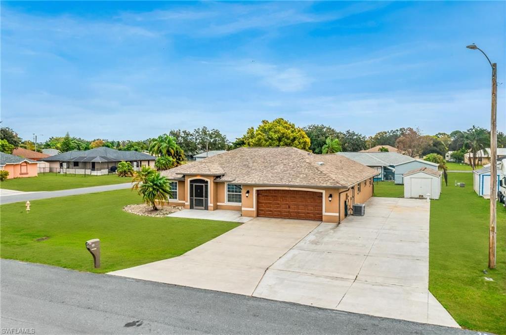 Single-story residence featuring a two-car garage with a wood-finish door, a screened front entryway, and a concrete driveway - Virtually Edited Image