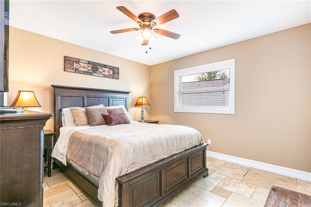Bright room featuring stone tile flooring, a window with white blinds, and a ceiling fan with integrated lighting - Virtually Edited Image