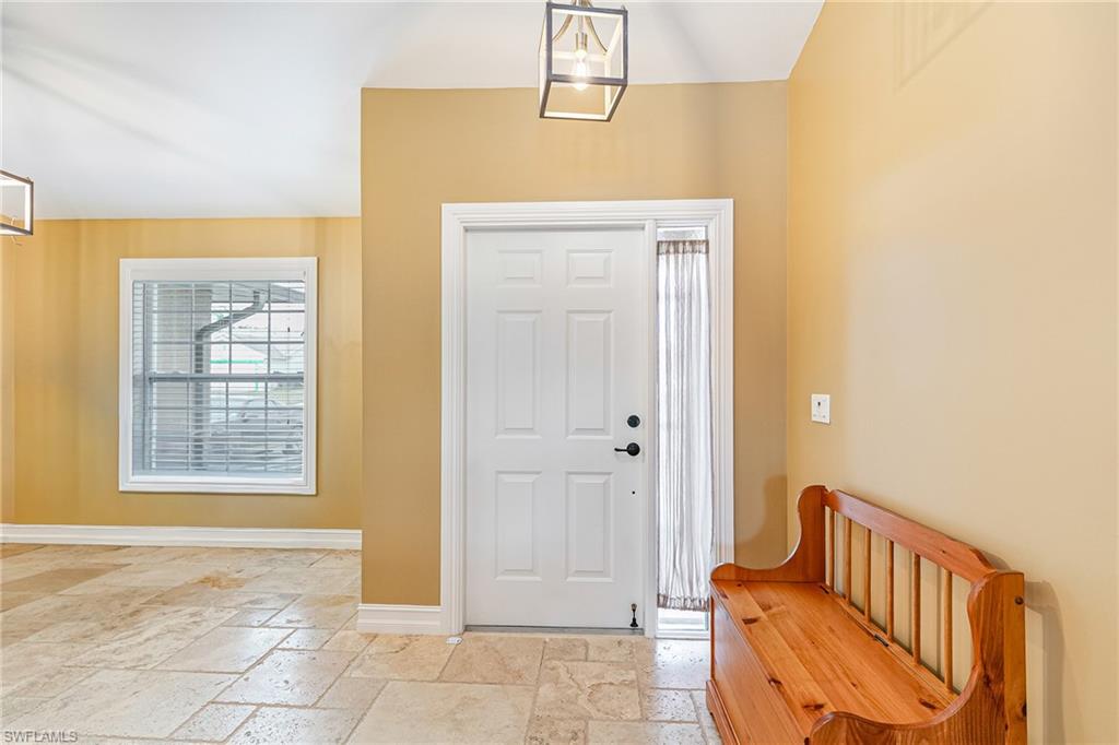 Foyer with light-toned tiled flooring, a white paneled entry door with sidelight, and a large window with blinds - Virtually Edited Image