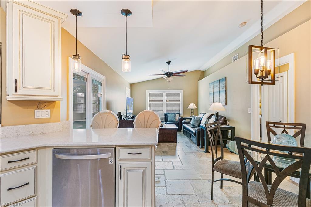 Kitchen island with light-toned countertop, integrated stainless steel dishwasher, and two pendant lights - Virtually Edited Image