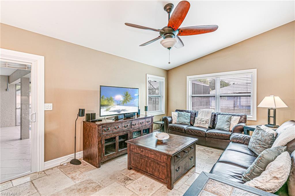 Living area featuring vaulted ceilings, a ceiling fan with integrated lighting, and tile flooring - Virtually Edited Image