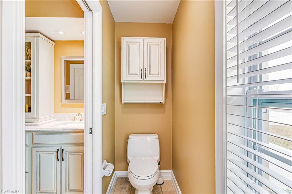 Bathroom featuring a window with horizontal blinds, built-in overhead cabinetry, and wood-finish flooring - Virtually Edited Image