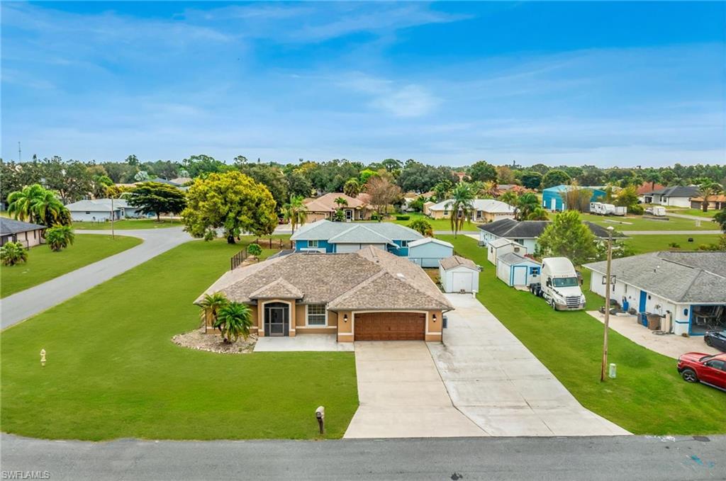 Single-story stucco residence featuring an attached two-car garage with a wood-finish door, a paved driveway, and a shingle roof - Virtually Edited Image