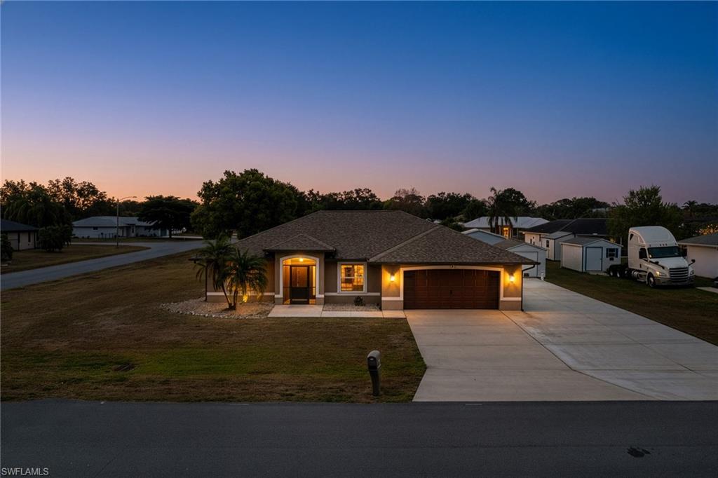 Single-story residence featuring a brown shingle roof and a spacious concrete driveway - Virtually Edited Image