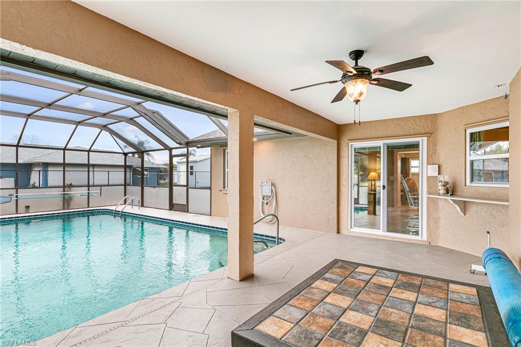 Screened-in pool area featuring a rectangular swimming pool, integrated spa, and a covered patio with a ceiling fan - Virtually Edited Image