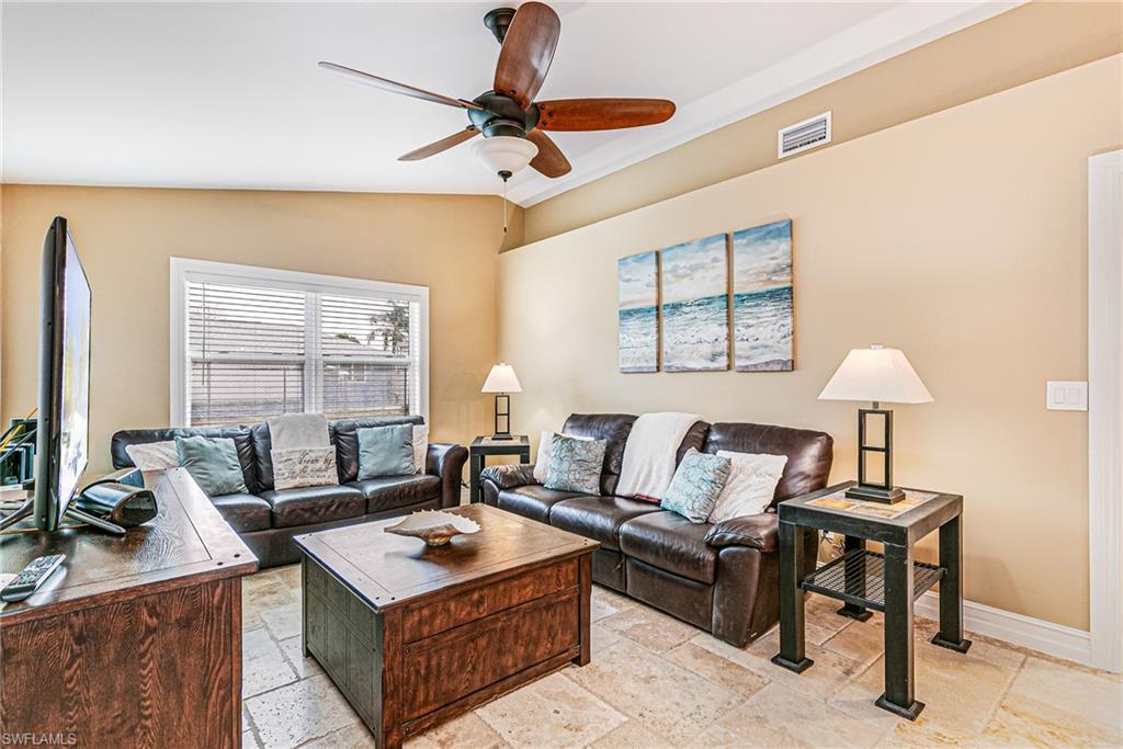 Living space featuring light-toned tile flooring, neutral wall paint, and white crown molding - Virtually Edited Image