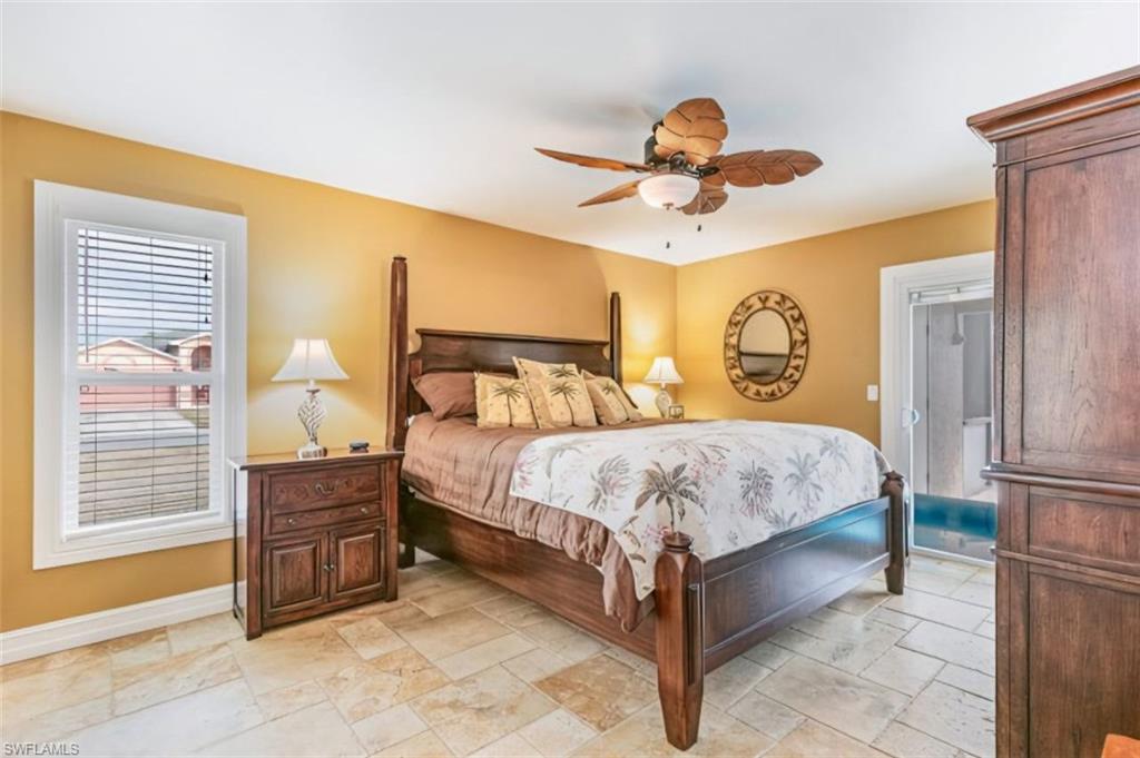 Bedroom featuring large-format tile flooring and a ceiling fan with tropical-inspired blades - Virtually Edited Image
