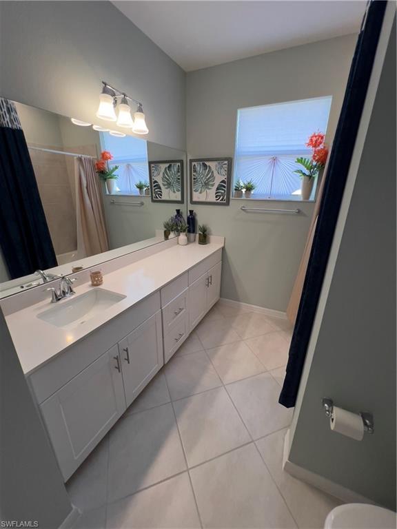 Bathroom with a wealth of natural light, vanity, a shower with curtain, and tile patterned flooring