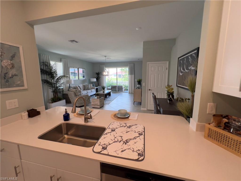 Kitchen featuring light tile patterned floors, white cabinetry, decorative light fixtures, and sink