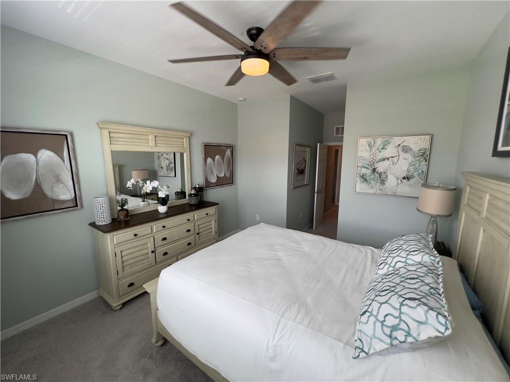 Carpeted bedroom featuring vaulted ceiling and ceiling fan