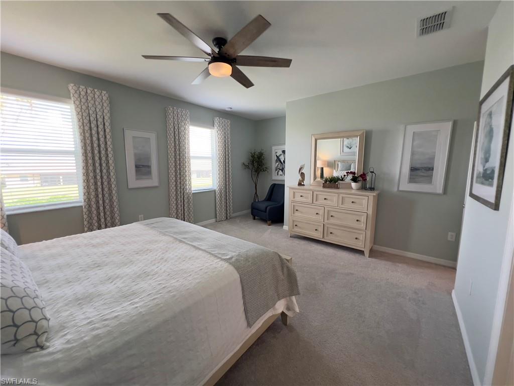 Bedroom with ceiling fan and light colored carpet