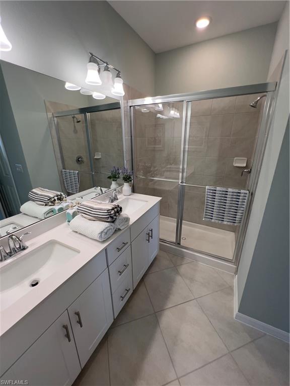 Bathroom with vanity, tile patterned flooring, and a shower with door