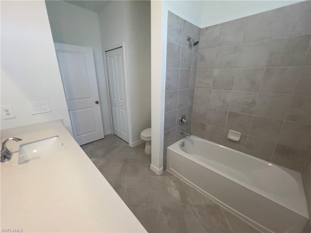 Full bathroom with tile patterned flooring, toilet, tiled shower / bath, and vanity