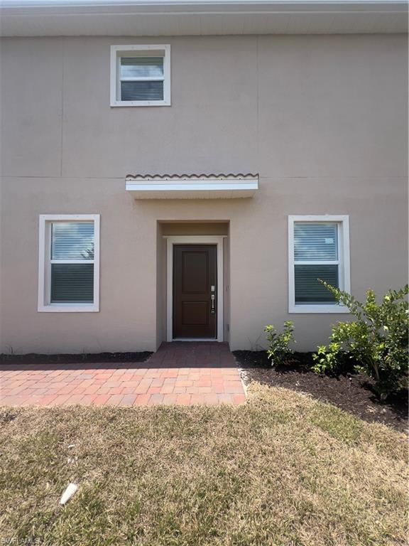 View of exterior entry featuring a lawn