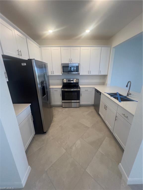 Kitchen featuring sink, white cabinetry, appliances with stainless steel finishes, and light tile patterned floors