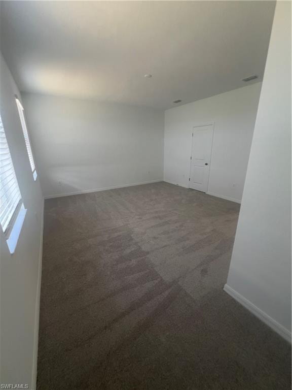 Unfurnished room featuring dark carpet