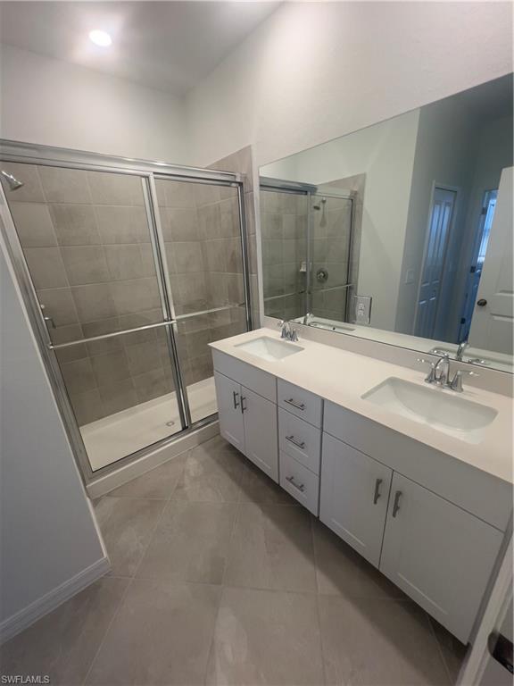Bathroom featuring tile patterned flooring, walk in shower, and vanity