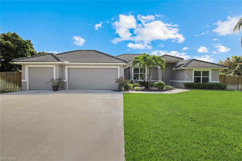 Contemporary stucco exterior with a dark tile roof, a two-car garage, a concrete driveway, and a verdant lawn