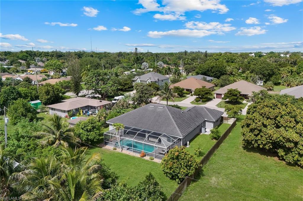 Aerial perspective showcasing a property featuring a screened-in swimming pool and a expansive grassy lawn
