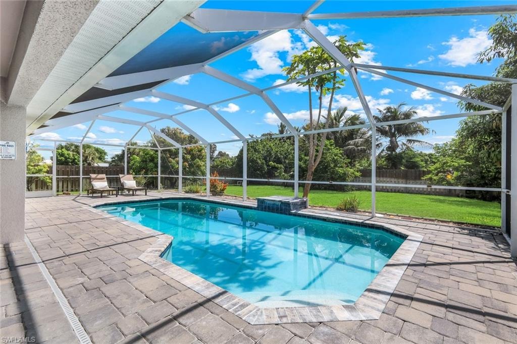 Screened-in pool deck featuring a geometric swimming pool with an integrated water feature and surrounding paver decking