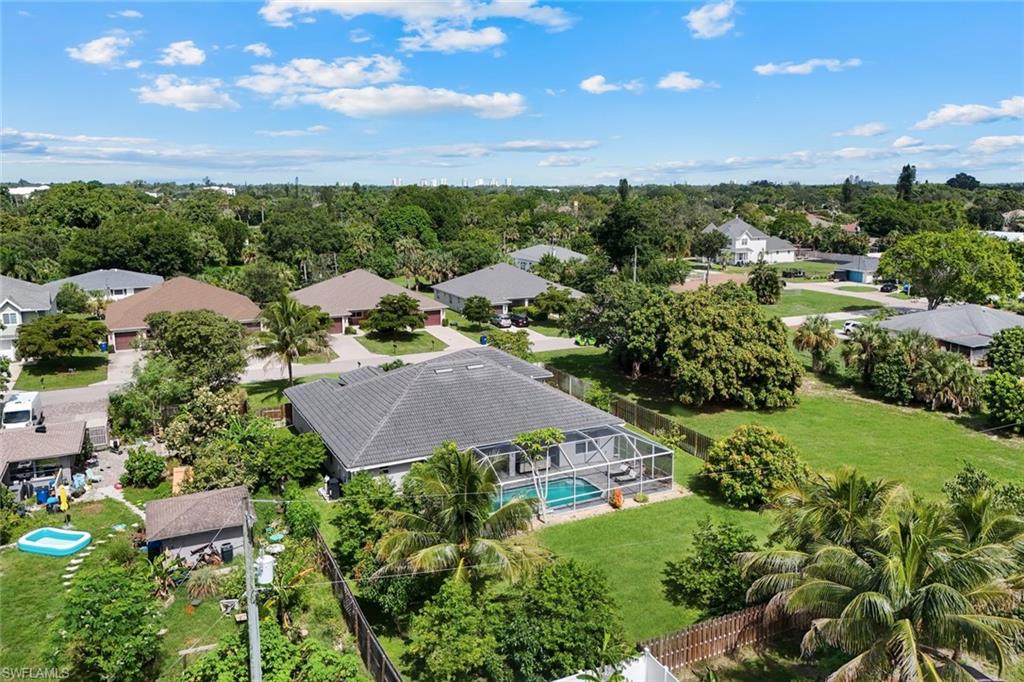 Expansive property featuring a screened-in pool, lush green lawn, mature trees, and a privacy fence