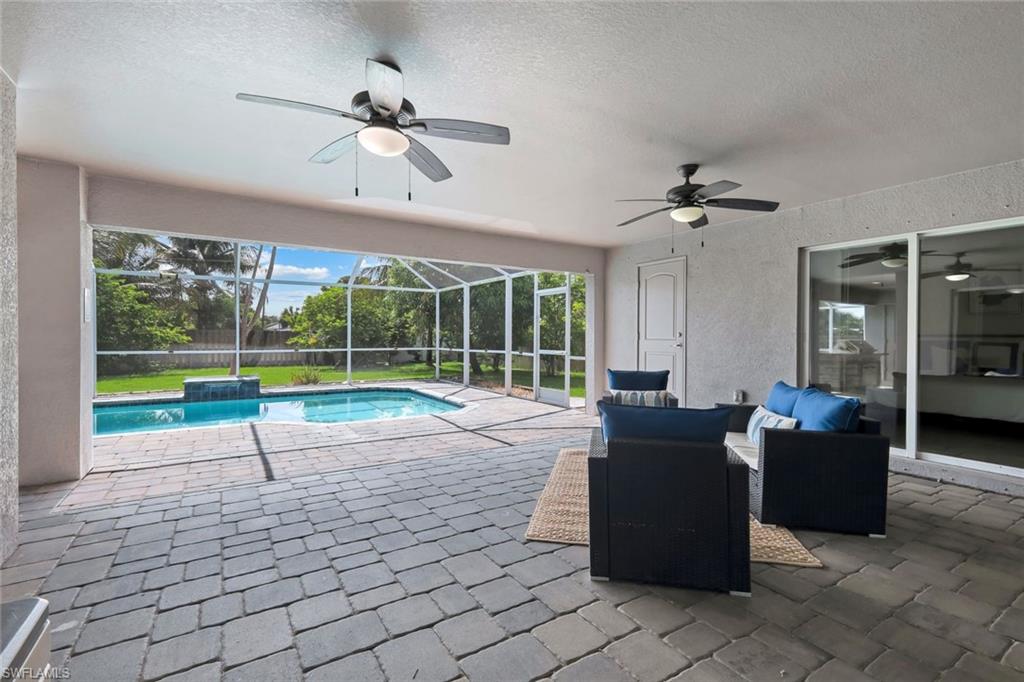Screened lanai featuring paver flooring, two ceiling fans, and a sparkling pool with a water feature