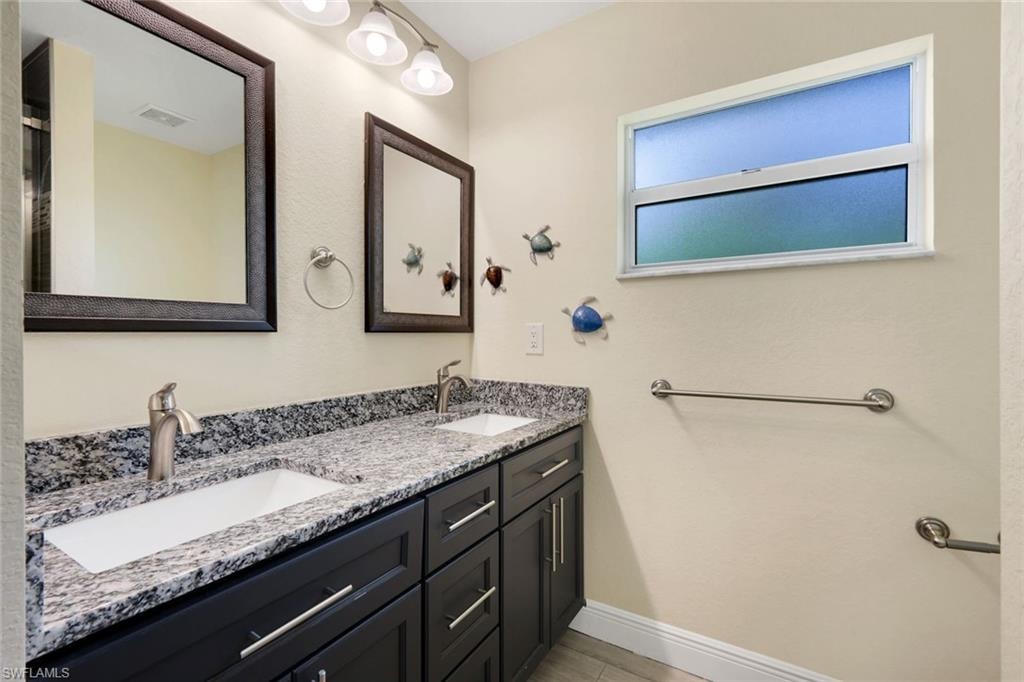 Double vanity featuring black cabinetry, granite-finish countertop, and undermount sinks
