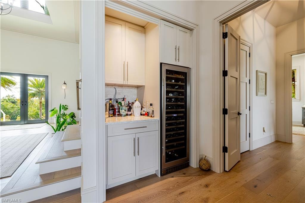 Built-in wet bar featuring white cabinetry, a stone countertop, and a stainless steel wine refrigerator