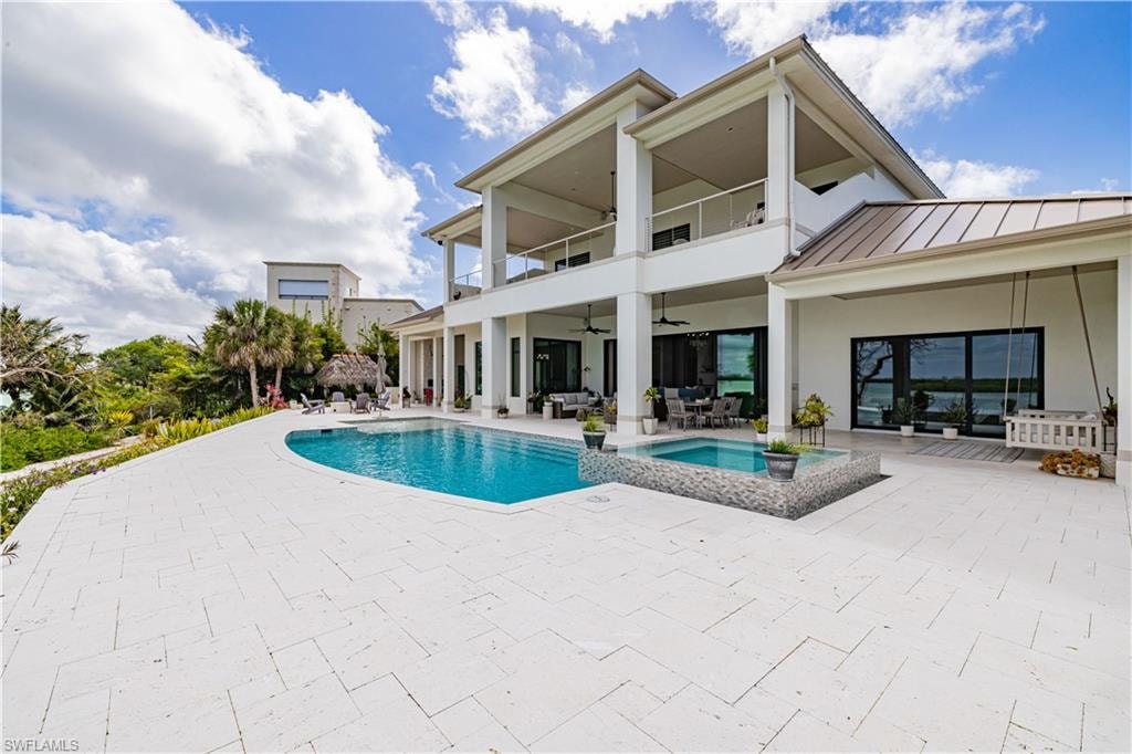 Expansive poolside patio featuring a rectangular swimming pool and integrated spa with mosaic tile surround