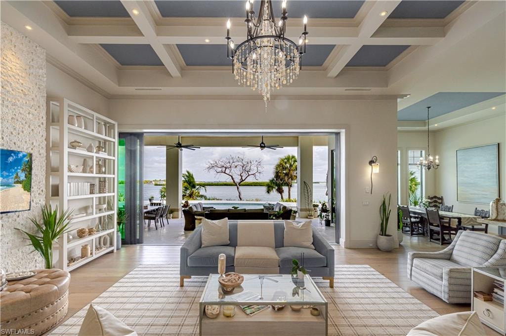 Spacious living area featuring a coffered ceiling, a substantial chandelier, and a built-in shelving unit