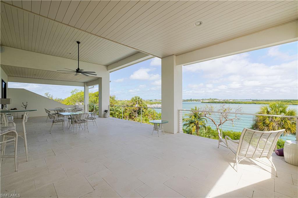 Expansive covered outdoor living space featuring light-toned tile flooring, a slatted ceiling, and an oversized ceiling fan