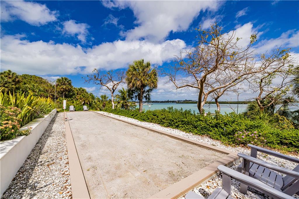 Bocce ball court featuring a gravel playing surface, bordered by white crushed stone and landscaping
