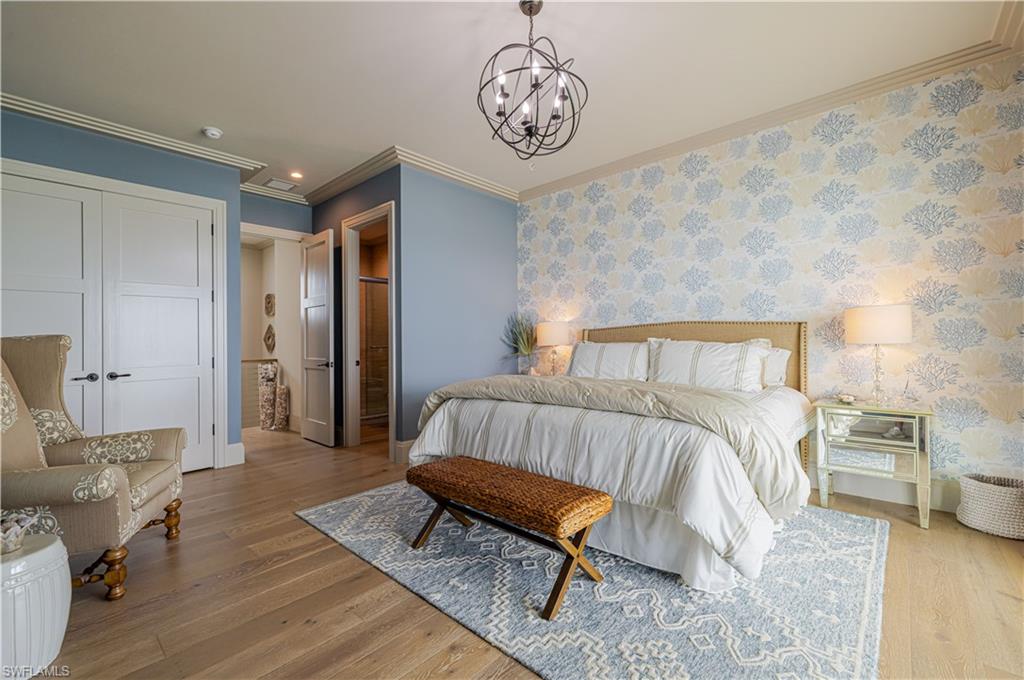 Bedroom featuring wood-finish flooring, a decorative accent wall, and crown molding