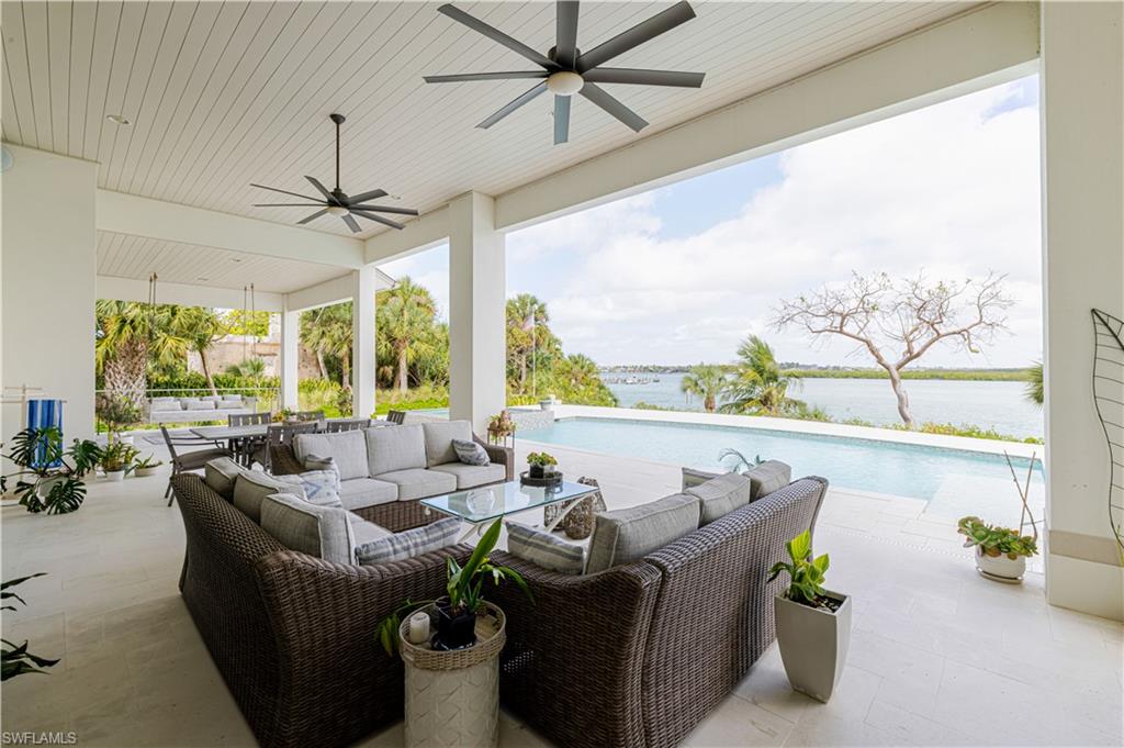 Expansive covered outdoor living space featuring a flat panel ceiling, two ceiling fans, and a light-colored tile floor