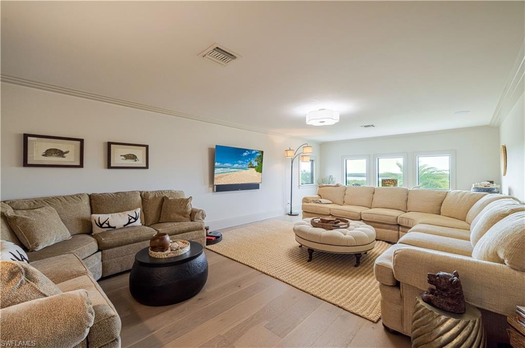 Spacious living area featuring light wood-finish flooring, white walls, and a multi-pane window configuration providing exterior views