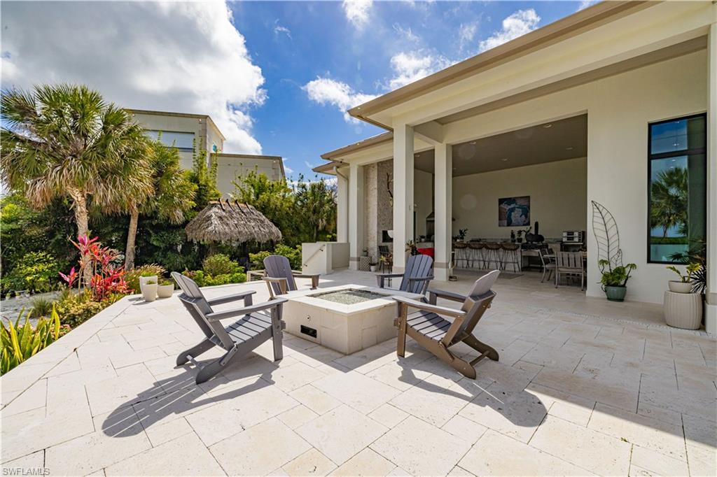 Expansive outdoor patio featuring light-toned pavers and a built-in fire pit